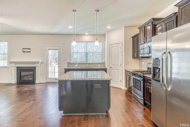 a kitchen with stainless steel appliances granite countertop a refrigerator a stove and a wooden floors