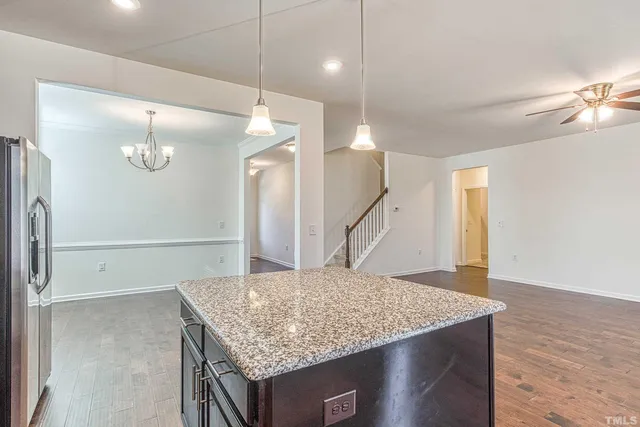 a kitchen with a table a refrigerator and wooden floor