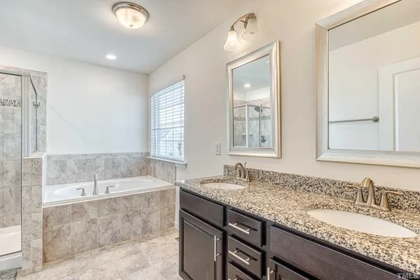 a bathroom with a granite countertop bathtub a sink and a large mirror