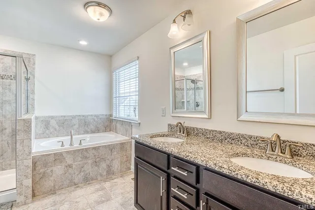 a bathroom with a granite countertop bathtub a sink and a large mirror