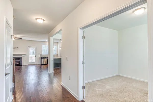 a view of a livingroom with wooden floor and kitchen view