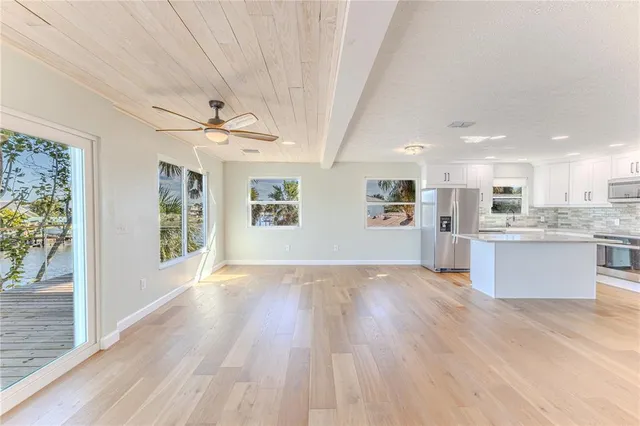 an empty room with wooden floor ceiling fan and windows