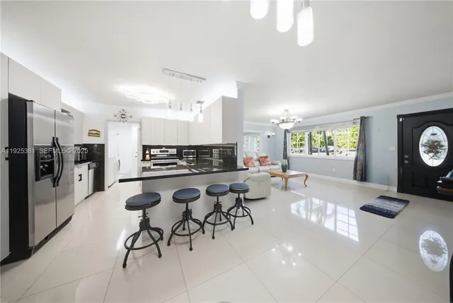 a open kitchen with stainless steel appliances kitchen island granite countertop a refrigerator a stove a oven with white cabinets and wooden floor