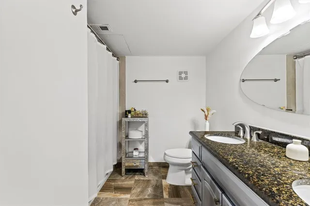 a bathroom with a granite countertop sink a toilet and a mirror