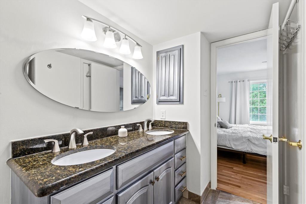 5626 Preston Oaks Road, Unit 51D Dallas, TX 75254 - Photo 18 of 19 a en suite bathroom with a granite countertop double vanity sink and a mirror