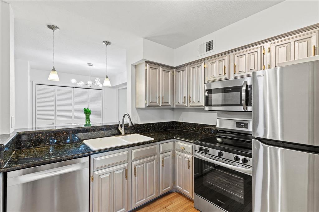 5626 Preston Oaks Road, Unit 51D Dallas, TX 75254 - Photo 8 of 19 a kitchen with granite countertop a sink stainless steel appliances and white cabinets