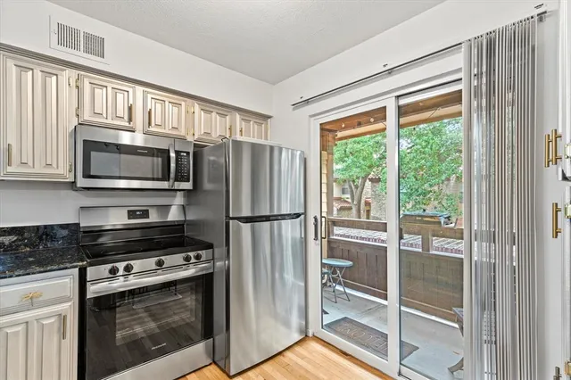 a kitchen with granite countertop a refrigerator and a stove top oven