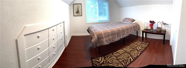 a bed sitting in a bedroom next to a window with wooden floor