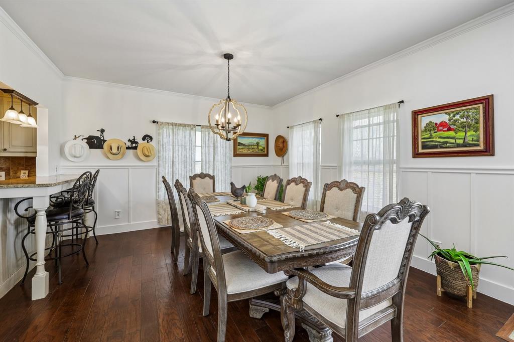 331 Radecke Road Krum, TX 76249 - Photo 11 of 40 Spacious dining area featuring dark wood-finish flooring, white wainscoting, crown molding, and two large windows