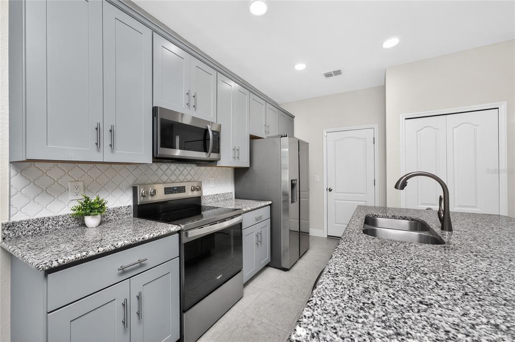27366 Deep Creek Boulevard Punta Gorda, FL 33983 - Photo 13 of 63 a kitchen with stainless steel appliances granite countertop a stove a sink dishwasher a refrigerator and microwave with wooden floor