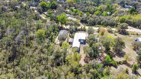 an aerial view of residential houses with outdoor space and trees