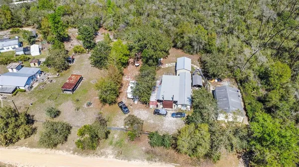 an aerial view of residential house with outdoor space and trees all around