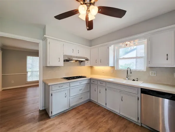 a kitchen with a sink stainless steel appliances cabinets and a window