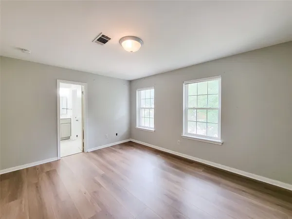 an empty room with wooden floor and windows