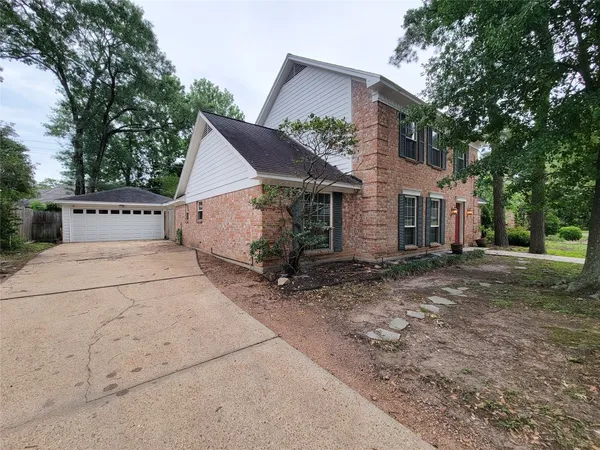 a view of a house with a yard and large tree