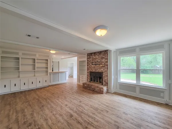 an empty room with windows fireplace and wooden floor