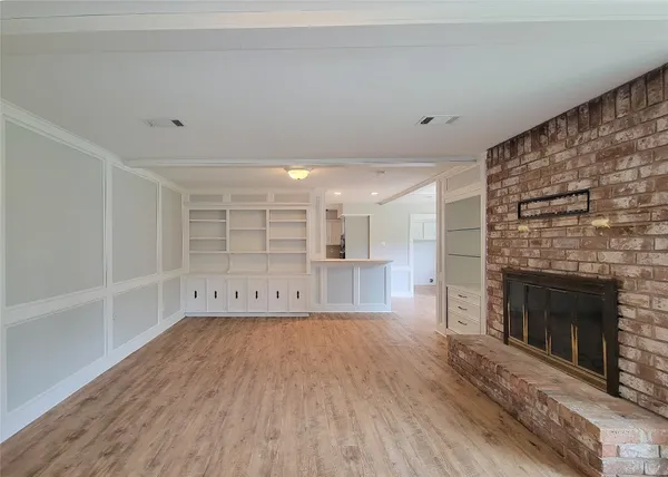 a view of empty room with wooden floor and fireplace