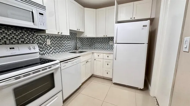 a kitchen with white cabinets and white appliances