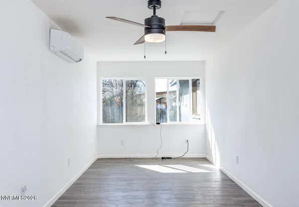 an empty room with wooden floor chandelier fan and windows