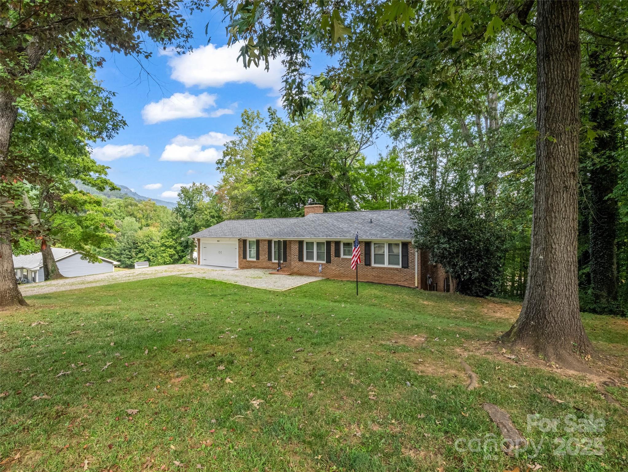 263 Blanton Street Columbus, NC 28722 - Photo 4 of 45 a view of a house with a big yard potted plants and large tree