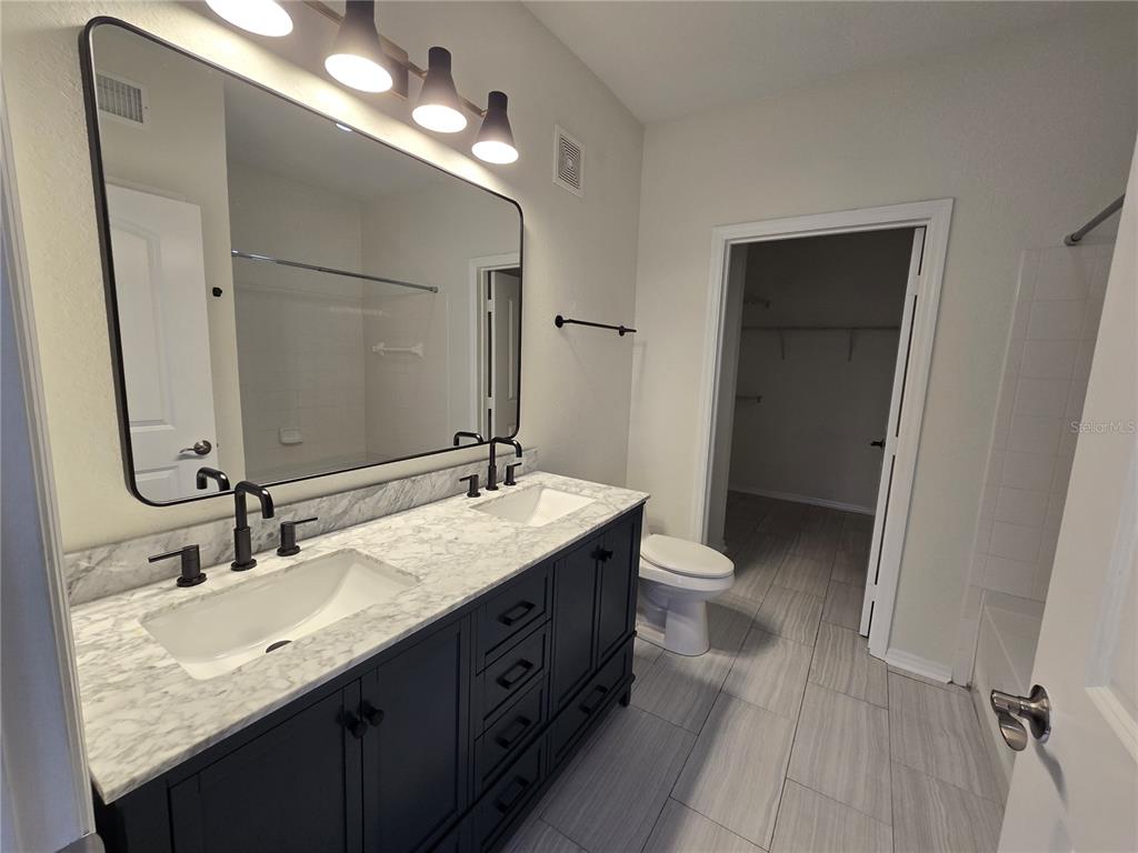 4221 West Spruce Street, Unit 2420 Tampa, FL 33607 - Photo 23 of 33 a bathroom with a granite countertop sink a toilet and a mirror