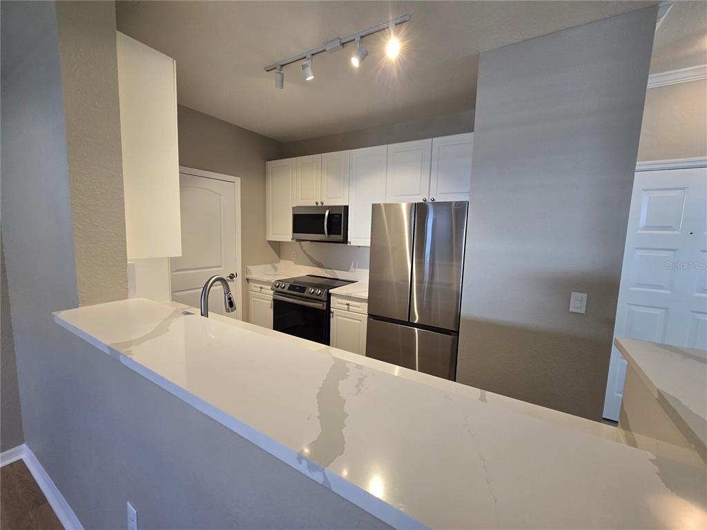 4221 West Spruce Street, Unit 2420 Tampa, FL 33607 - Photo 10 of 33 a large kitchen with stainless steel appliances a refrigerator a sink a stove a microwave and island