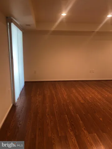 an empty room with wooden floor and windows with curtains