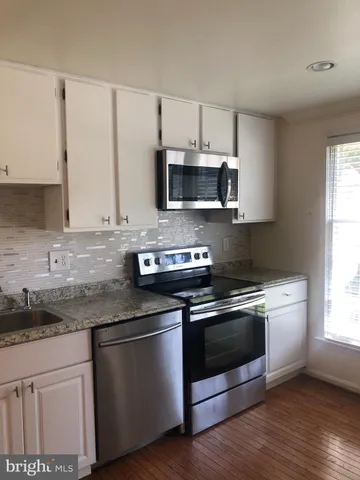 a kitchen with granite countertop white cabinets and stainless steel appliances