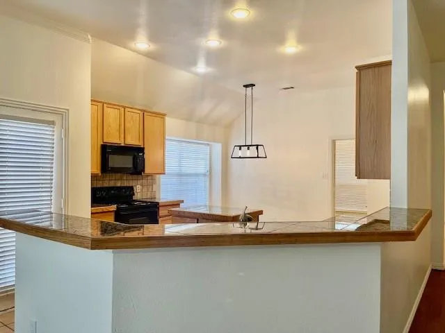 a view of a kitchen with kitchen island a sink appliances and a counter top space