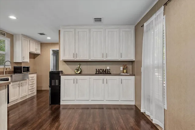 a kitchen with stainless steel appliances granite countertop a stove top oven a sink and white cabinets with wooden floor