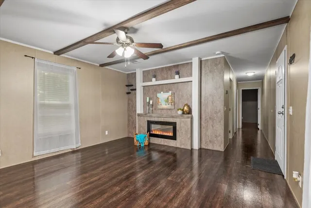 a view of an empty room with wooden floor and a ceiling fan