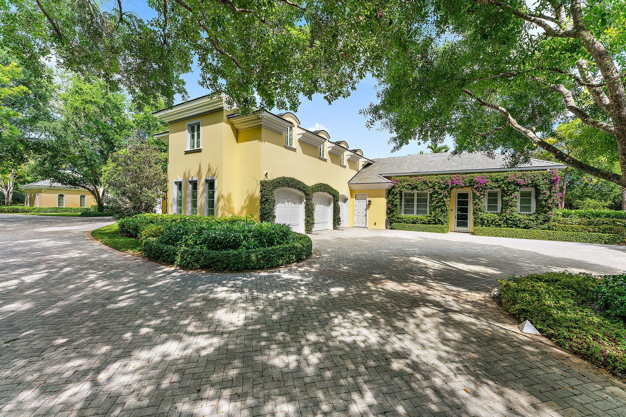 124 Bears Club Drive Jupiter, FL 33477 - Photo 6 of 67 a view of a white house with a yard plants and large tree
