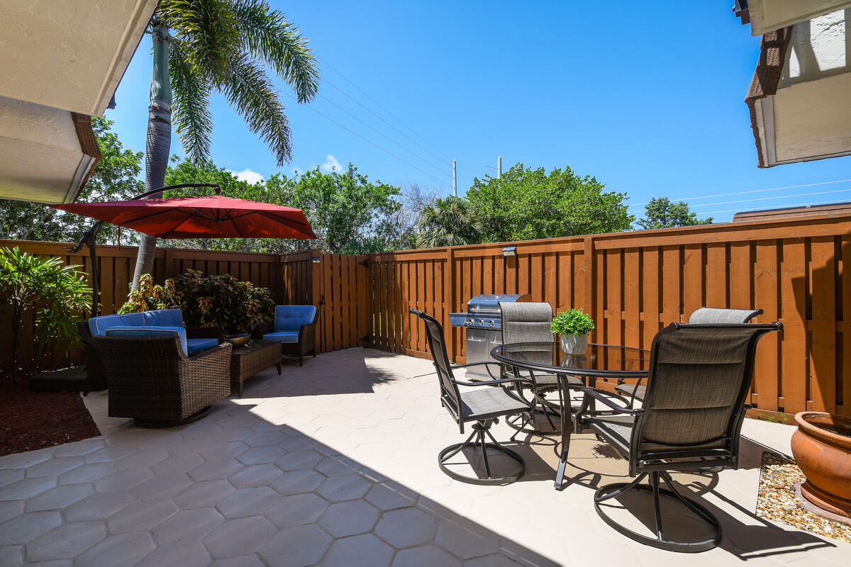 3900 County Line Road, Unit 9D Tequesta, FL 33469 - Photo 13 of 34 a view of a patio with a dining table and chairs with a wooden deck