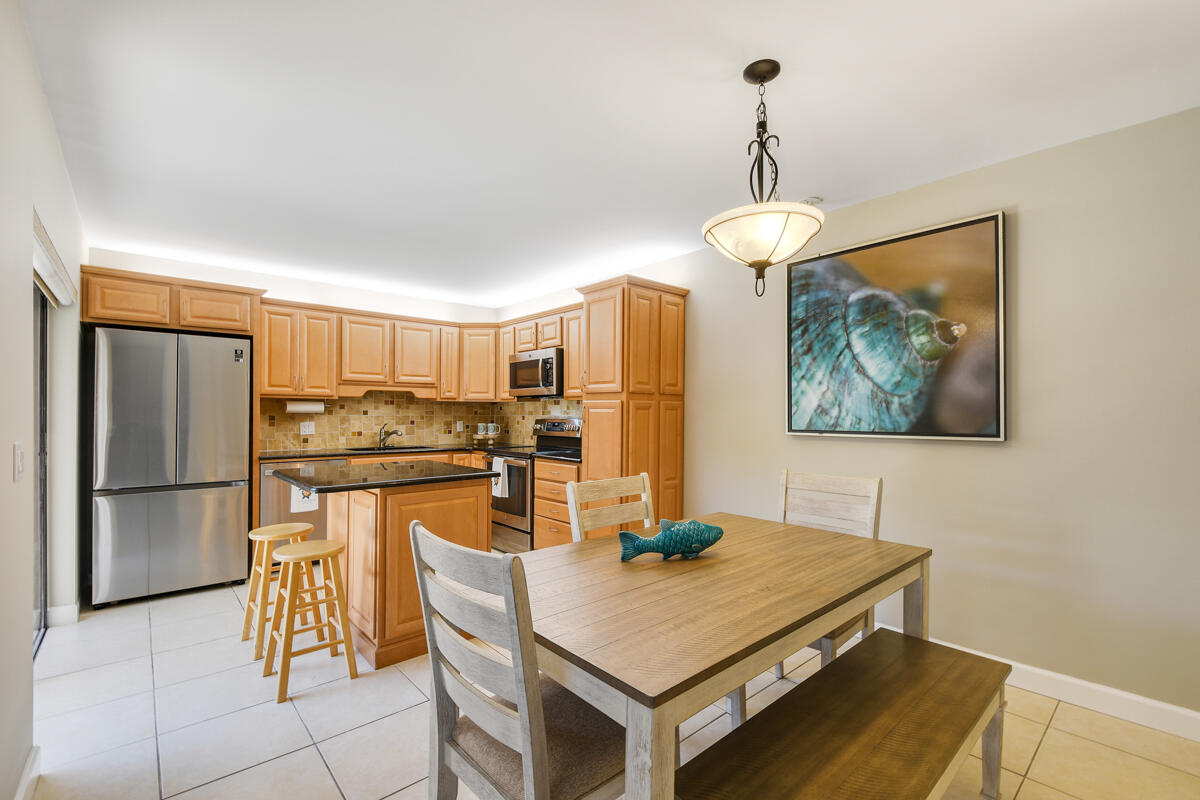 3900 County Line Road, Unit 9D Tequesta, FL 33469 - Photo 4 of 34 a kitchen with stainless steel appliances granite countertop a refrigerator a stove a sink a dining table and chairs with wooden floor