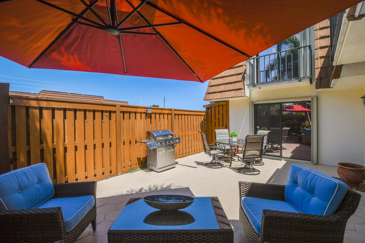 3900 County Line Road, Unit 9D Tequesta, FL 33469 - Photo 6 of 34 a view of a patio with table and chairs under an umbrella
