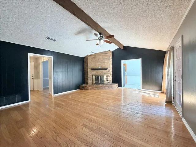 a view of an empty room with window and wooden floor