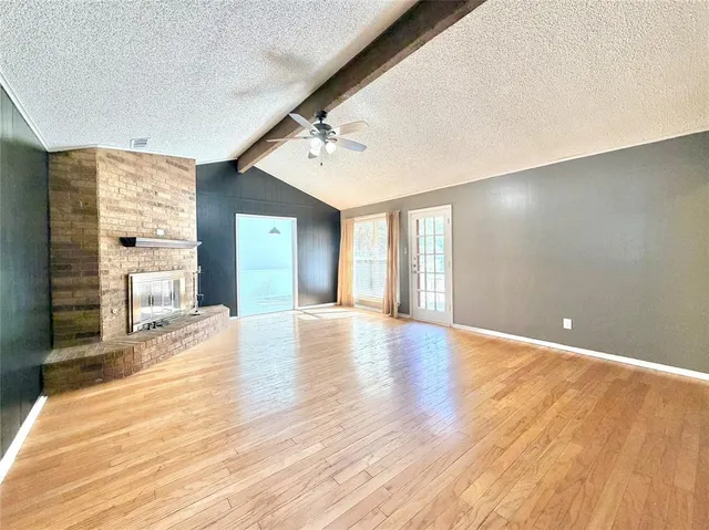 a view of an empty room with window and wooden floor