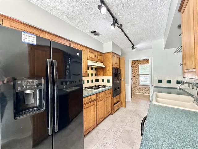 a large kitchen with stainless steel appliances kitchen island granite countertop a refrigerator and a sink