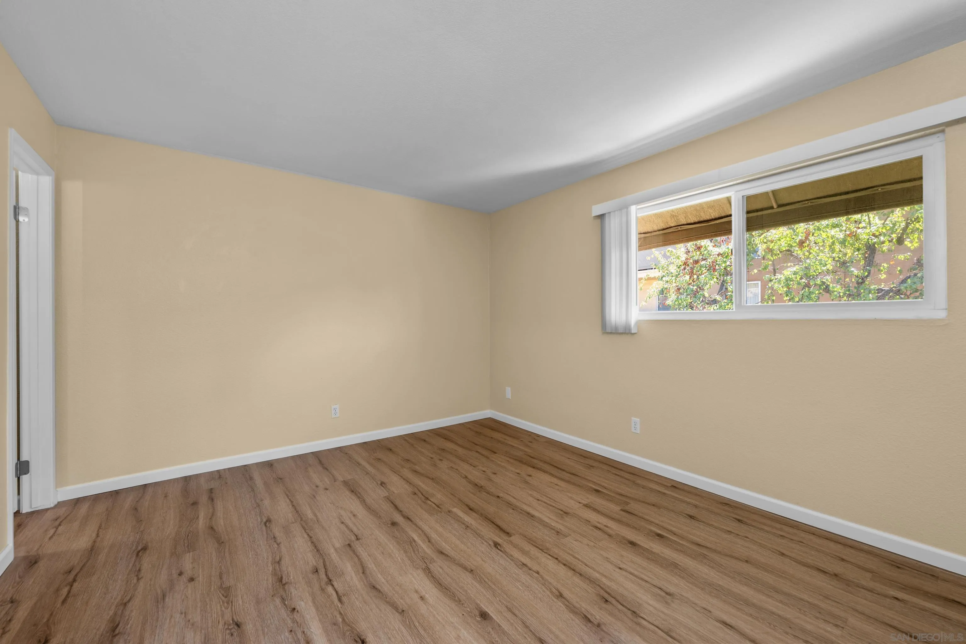 6911 Alvarado Road, Unit 20 San Diego, CA 92120 - Photo 16 of 28 a view of an empty room with wooden floor and a window