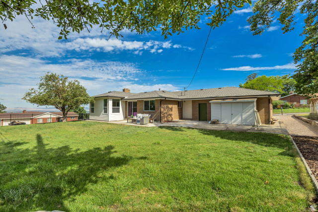 1168 East Center Street Bountiful, UT 84010 - Photo 35 of 38 Expansive green lawn surrounds the property, featuring a concrete patio and sunroom extension with multiple windows