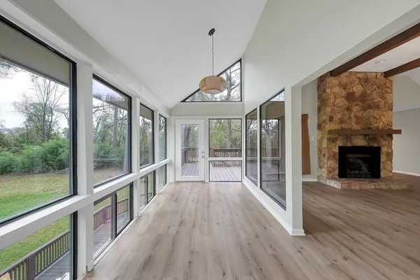 a view of a room with wooden floor a fireplace and windows