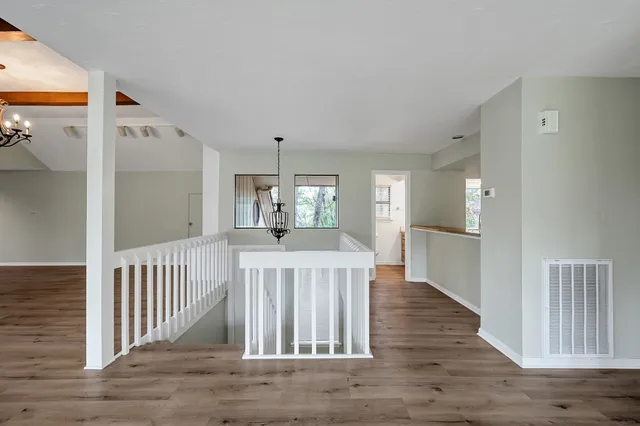 a view of a hallway with wooden floor and windows