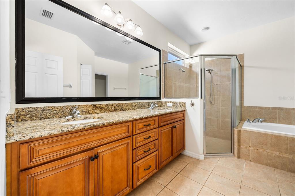 7638 Southwest 80th Drive Gainesville, FL 32608 - Photo 26 of 48 a bathroom with a granite countertop sink a mirror and a bathtub