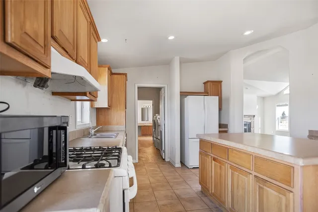 a kitchen with stainless steel appliances granite countertop a sink a stove and a refrigerator