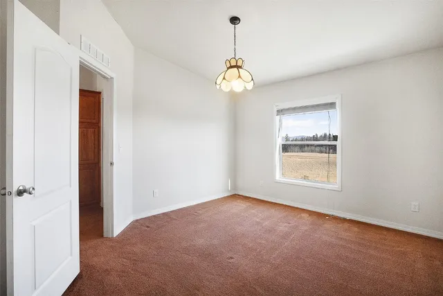 a view of an empty room with window and chandelier fan