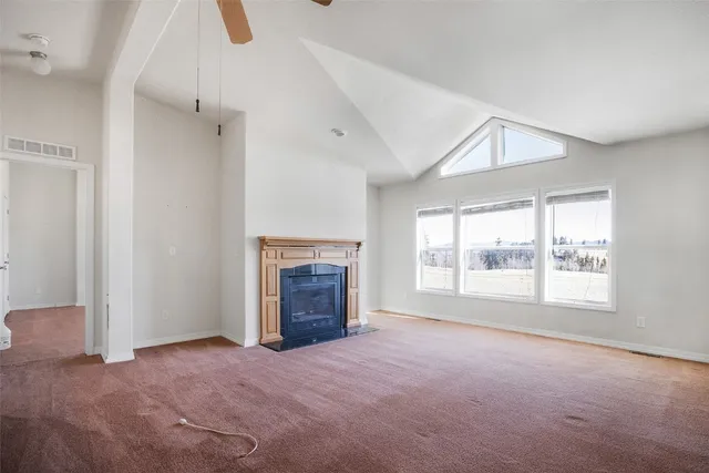 an empty room with windows and fireplace