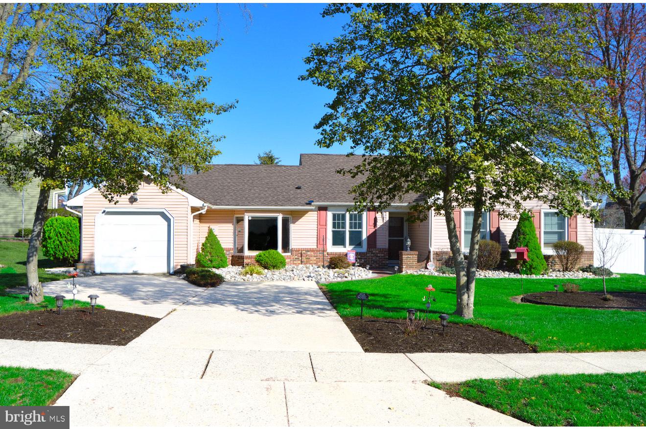 a front view of a house with a garden and trees