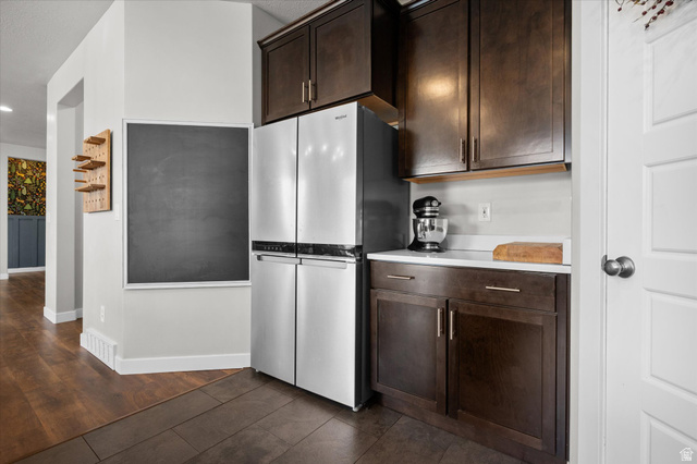 3359 Eurasian Crane Road Clinton, UT 84015 - Photo 6 of 71 Kitchen featuring dark wood finish cabinetry, freestanding refrigerator, and dark tile patterned flooring