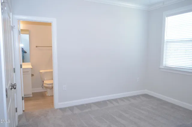 an empty room and a bathroom with a toilet