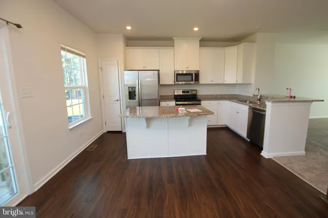 a kitchen with kitchen island wooden floors white appliances and cabinets